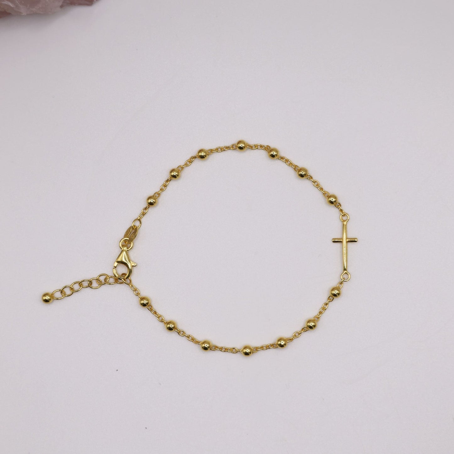 Dainty gold cross bracelet with bead accents on a delicate chain, displayed on a white background – minimalist religious jewelry gift for her