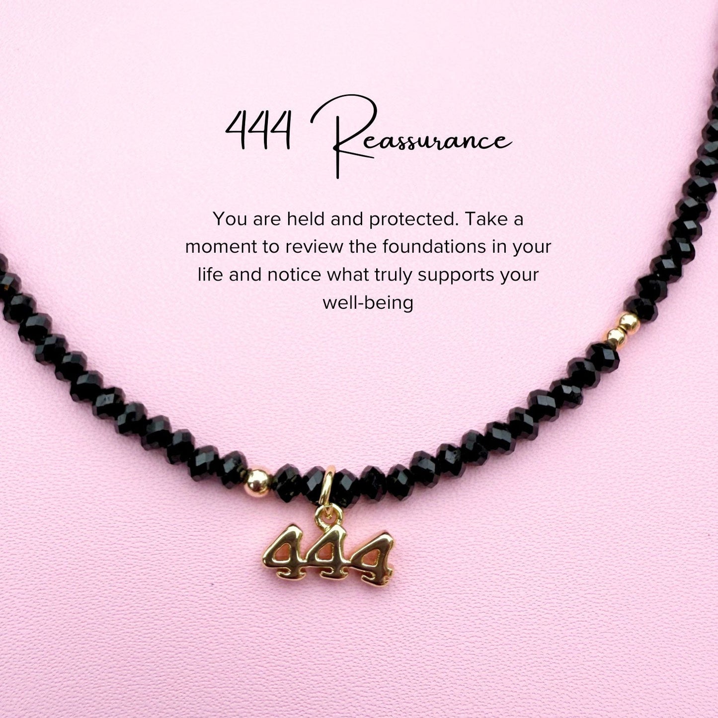 Black tourmaline beaded Necklace with '444' angel charm on a pink background