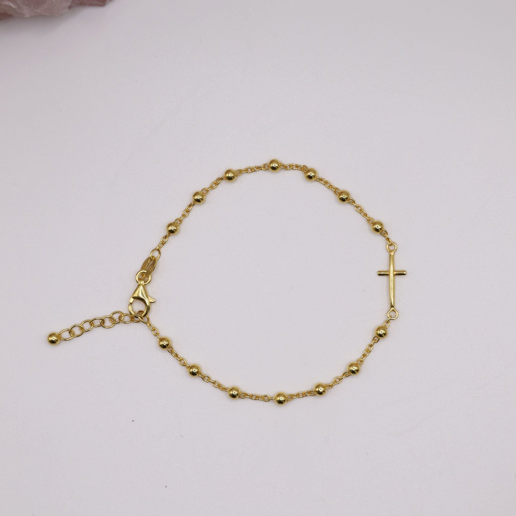 Dainty gold cross bracelet with bead accents on a delicate chain, displayed on a white background – minimalist religious jewelry gift for her