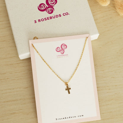 Dainty gold filled cross necklace for girls on a white card with the 3 rosebuds co logo
