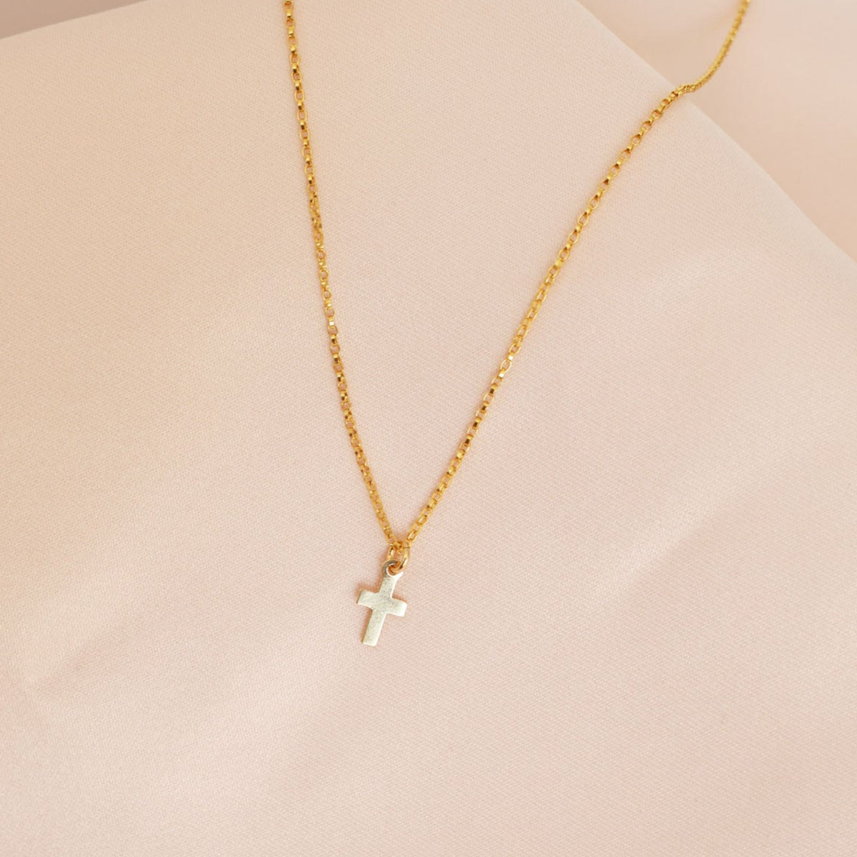 Gold Necklace with a cross pendant for girls on a pink background