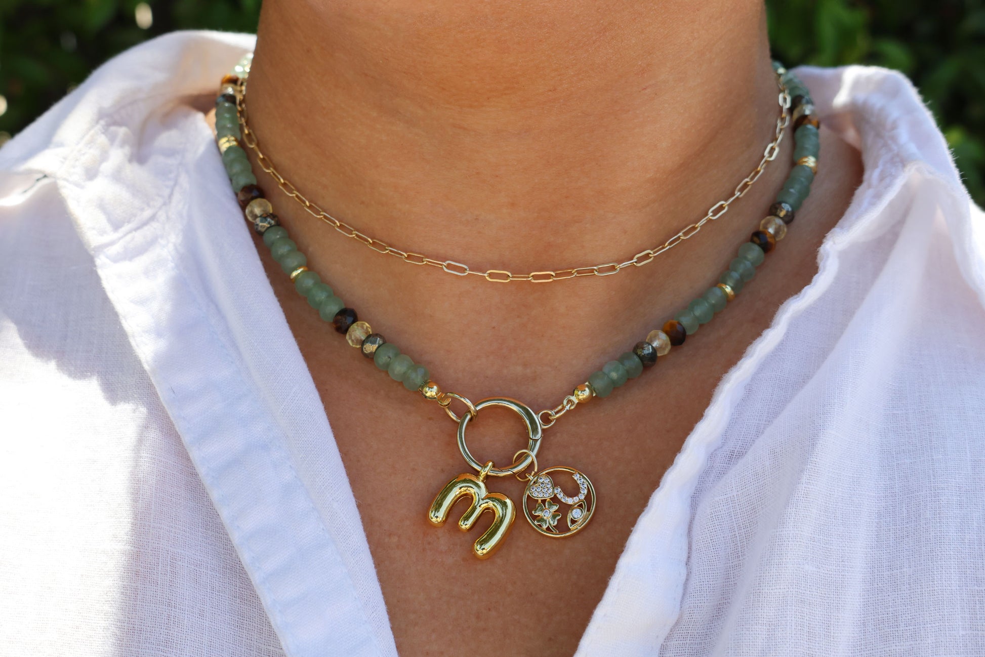 Necklace with green aventurine, citrine, pyrite, and tiger's eye crystals and gold charms on a white shirt