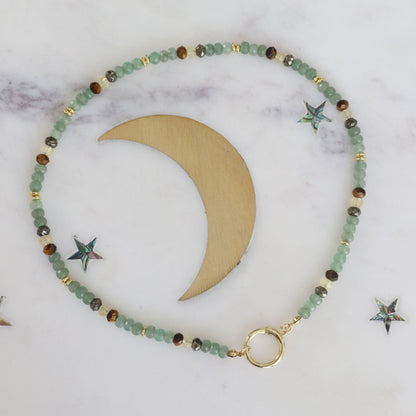 Prosperity crystal necklace with green aventurine, pyrite, tiger's eye, and citrine. Finished with a gold accent crescent on a marble background