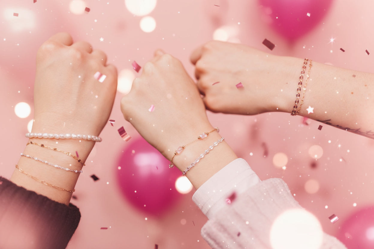 3 wrists with permanent jewelry bracelets on a pink background