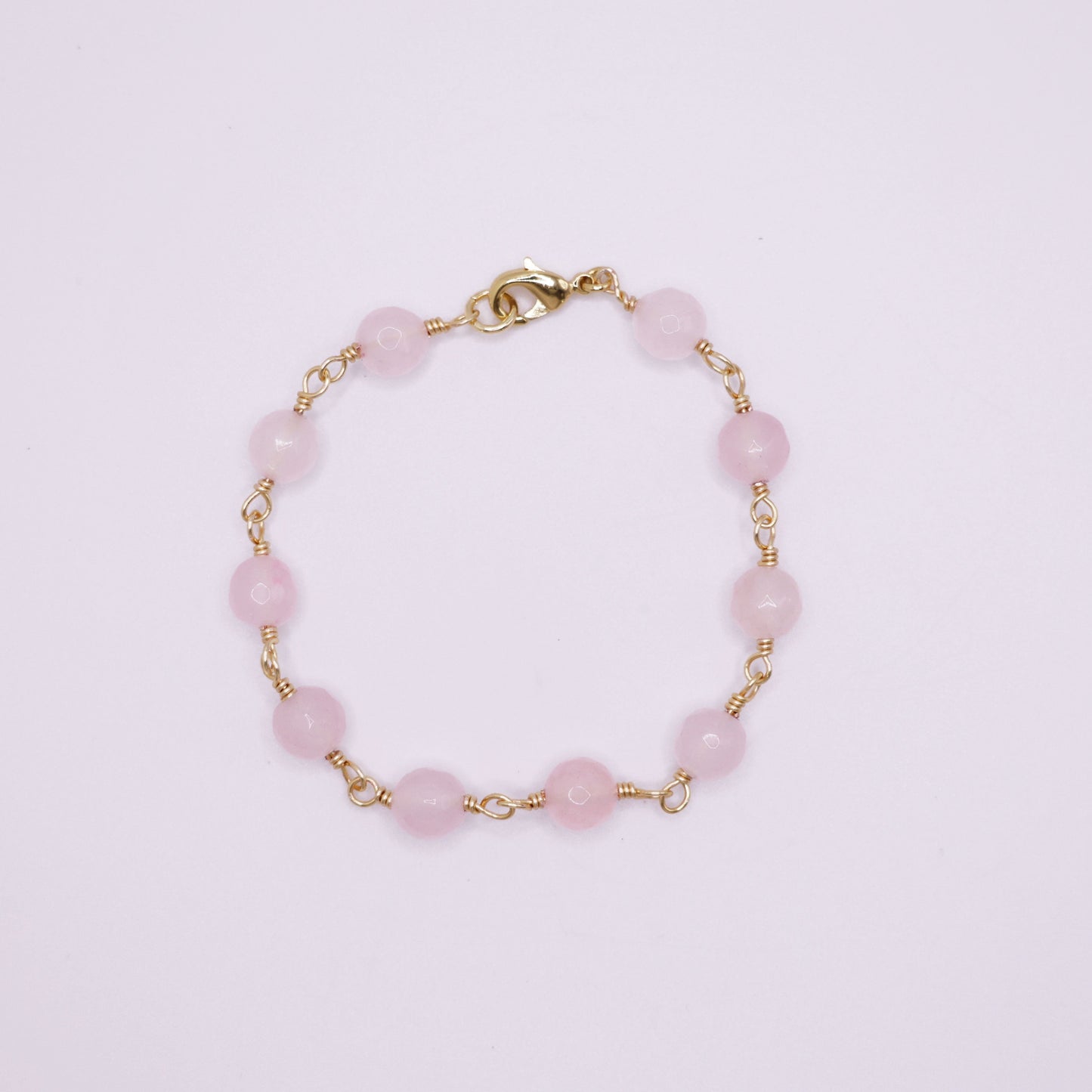Rose Quartz rosary beaded bracelet on a light pink background