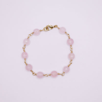 Rose Quartz rosary beaded bracelet on a light pink background