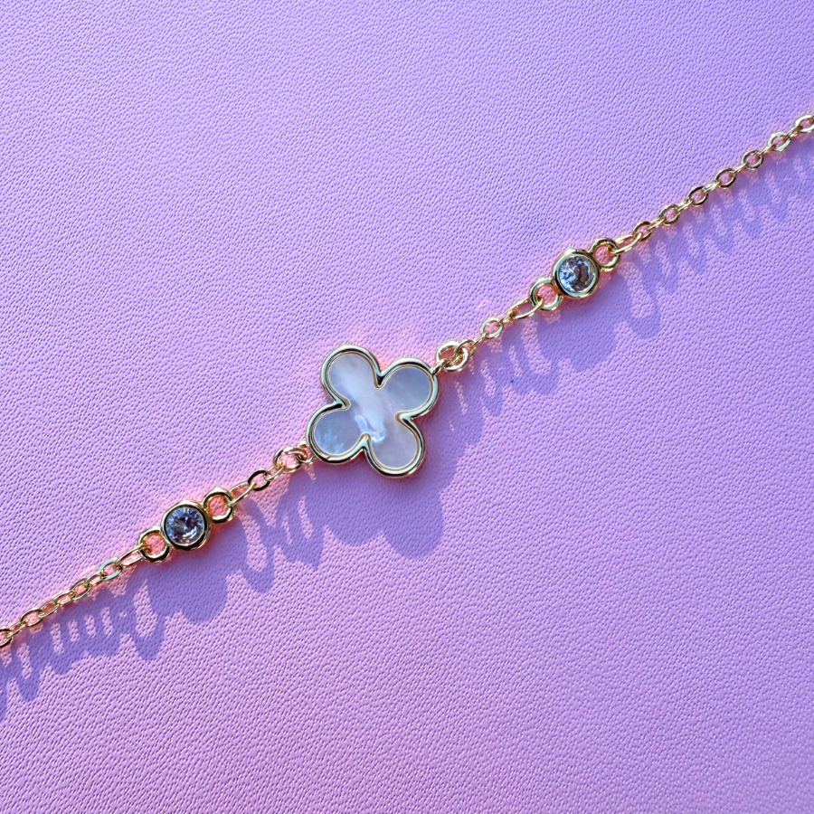 Delicate bracelet with a clover-shaped charm on a purple background