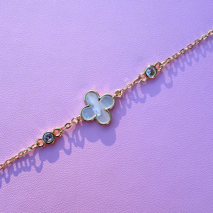 Delicate bracelet with a clover-shaped charm on a purple background